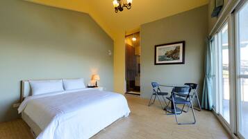 Habitación de hotel con una cama grande, un escritorio con sillas, un cuadro en la pared y vistas por la ventana.