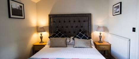 A neatly made bed with a colorful checkered blanket, two bedside lamps, and a headboard with a tufted design.