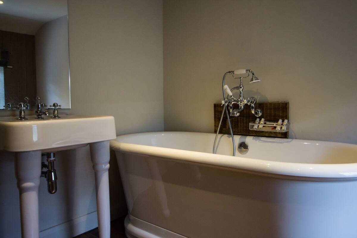 A bathroom with a white bathtub, a sink, and a mirror.