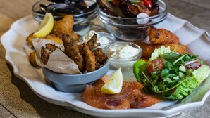 A plate of food including fried fish, mussels, and a salad with a lemon wedge.