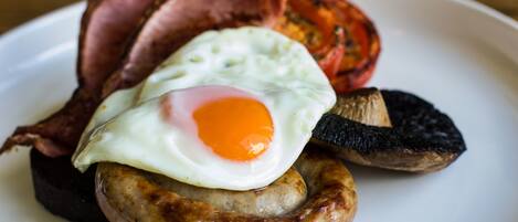 A plate with a sausage, a fried egg, and a slice of bacon.