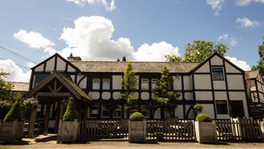A traditional Tudor-style building with a symmetrical facade, multiple windows, and a gated entrance.