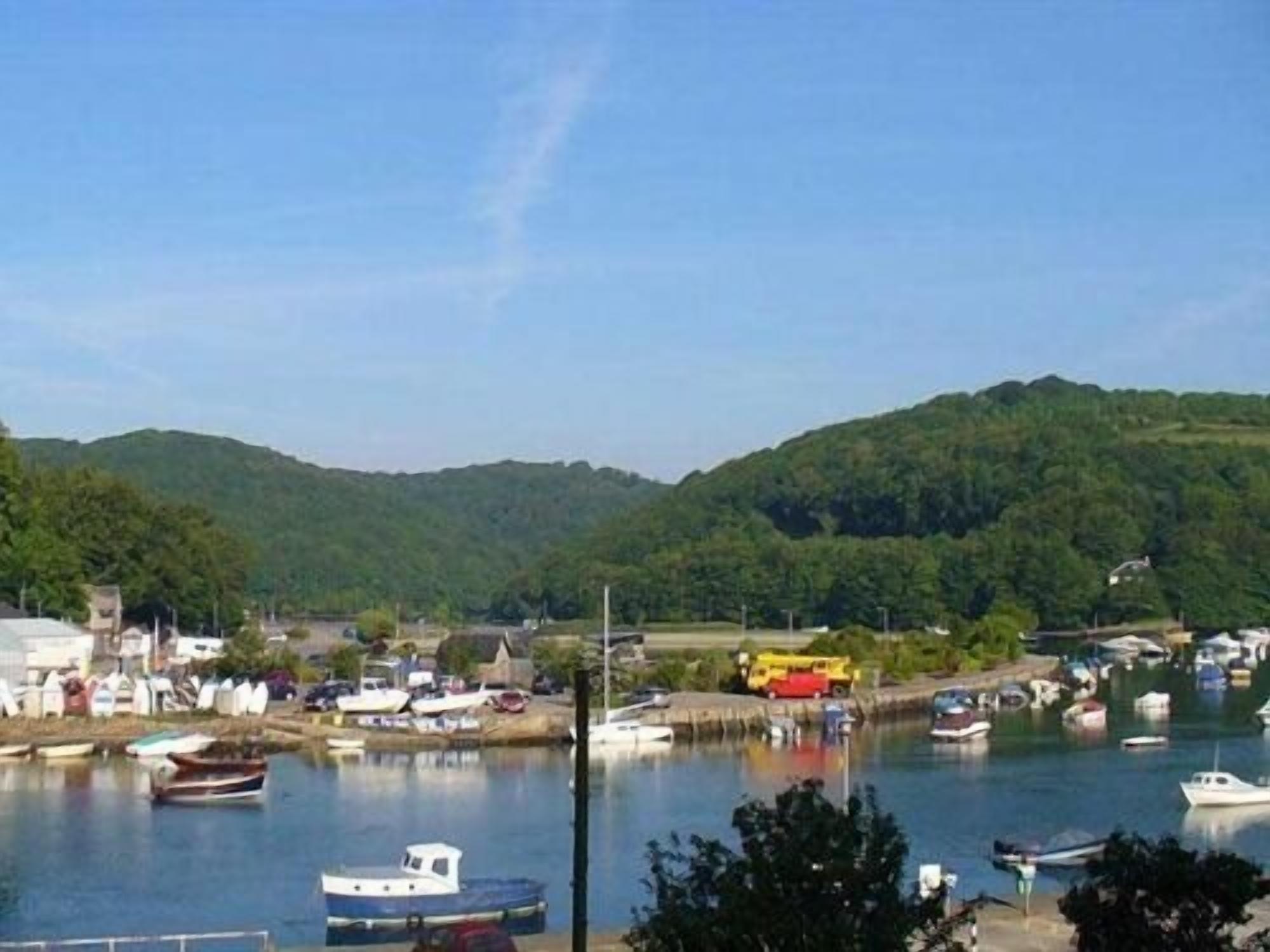Une ville côtière où des bateaux sont amarrés dans un port de plaisance, le tout étant entouré de collines.