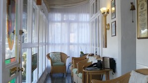 A corridor with wicker furniture, a table with a phone and papers, and framed pictures on the wall. - Dolphin Guest House (Looe)