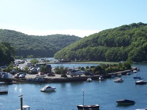 A marina with boats docked, surrounded by lush green hills. - Dolphin Guest House (Looe)