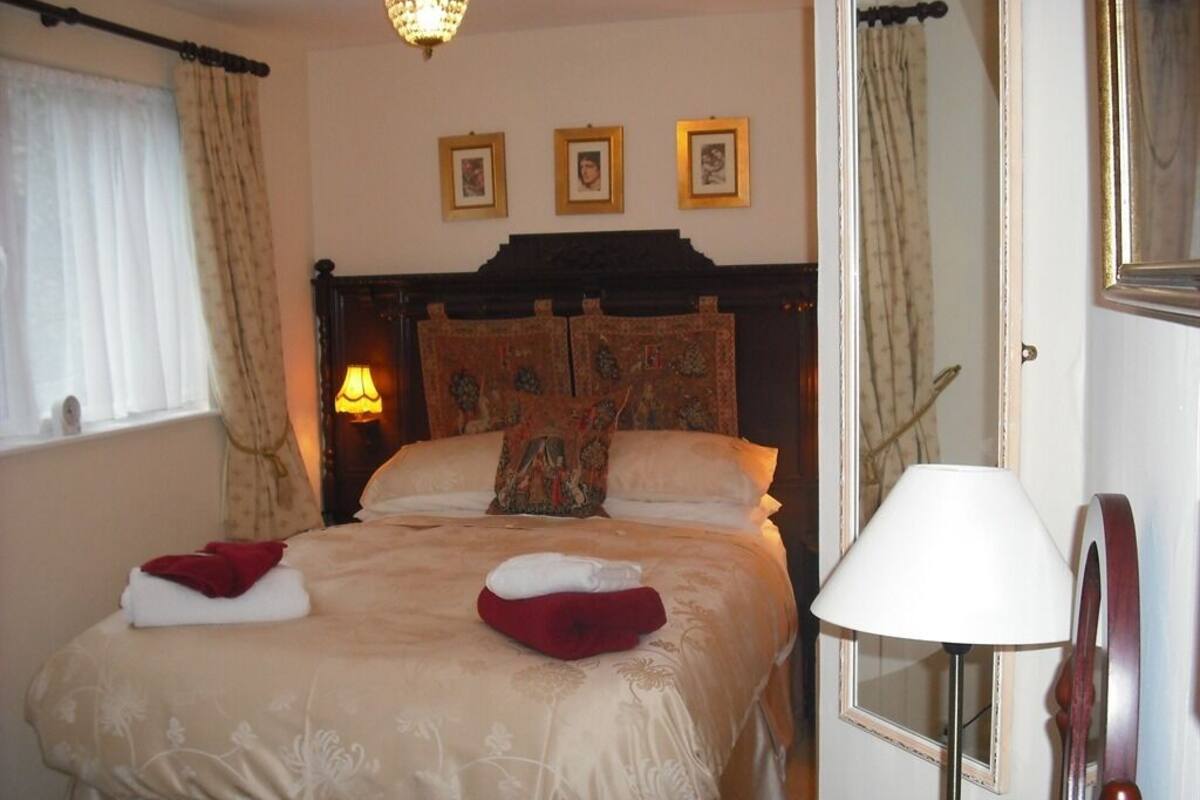 A neatly made bed with a headboard, a bedside lamp, and a mirror.
