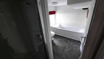 A bathroom with a bathtub, toilet, and shower area.