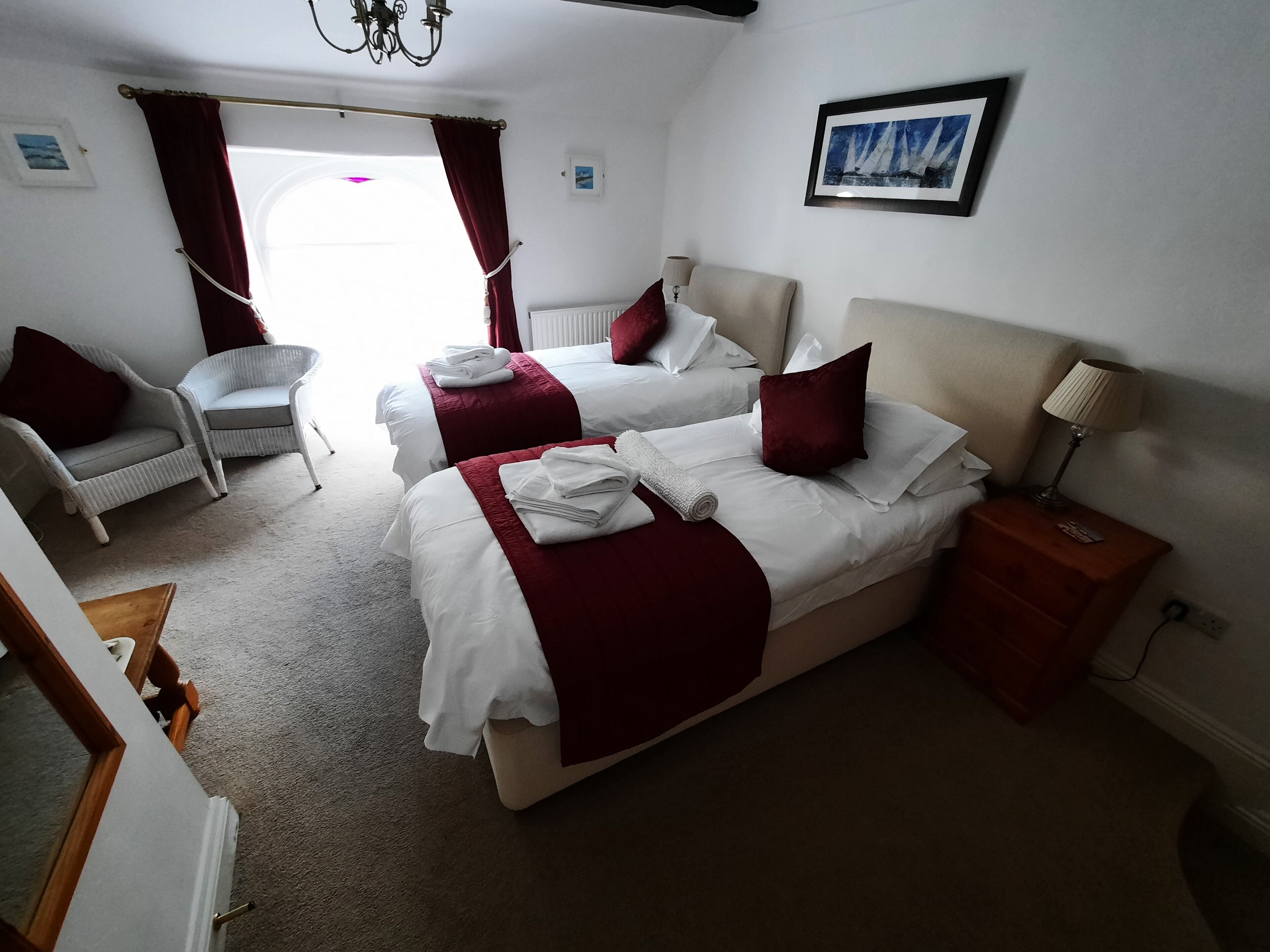 Une chambre d’hôtel avec deux lits, une chaise, une table de chevet et un tableau au mur.