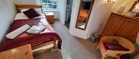 A bedroom with a bed, bedside table, lamp, and a mirror.