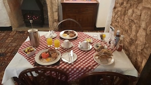 A breakfast setting with a checkered tablecloth, plates of eggs, bacon, and toast, a coffee pot, juice glasses, and a kettle. - The White Cottage B&B (Colyton)