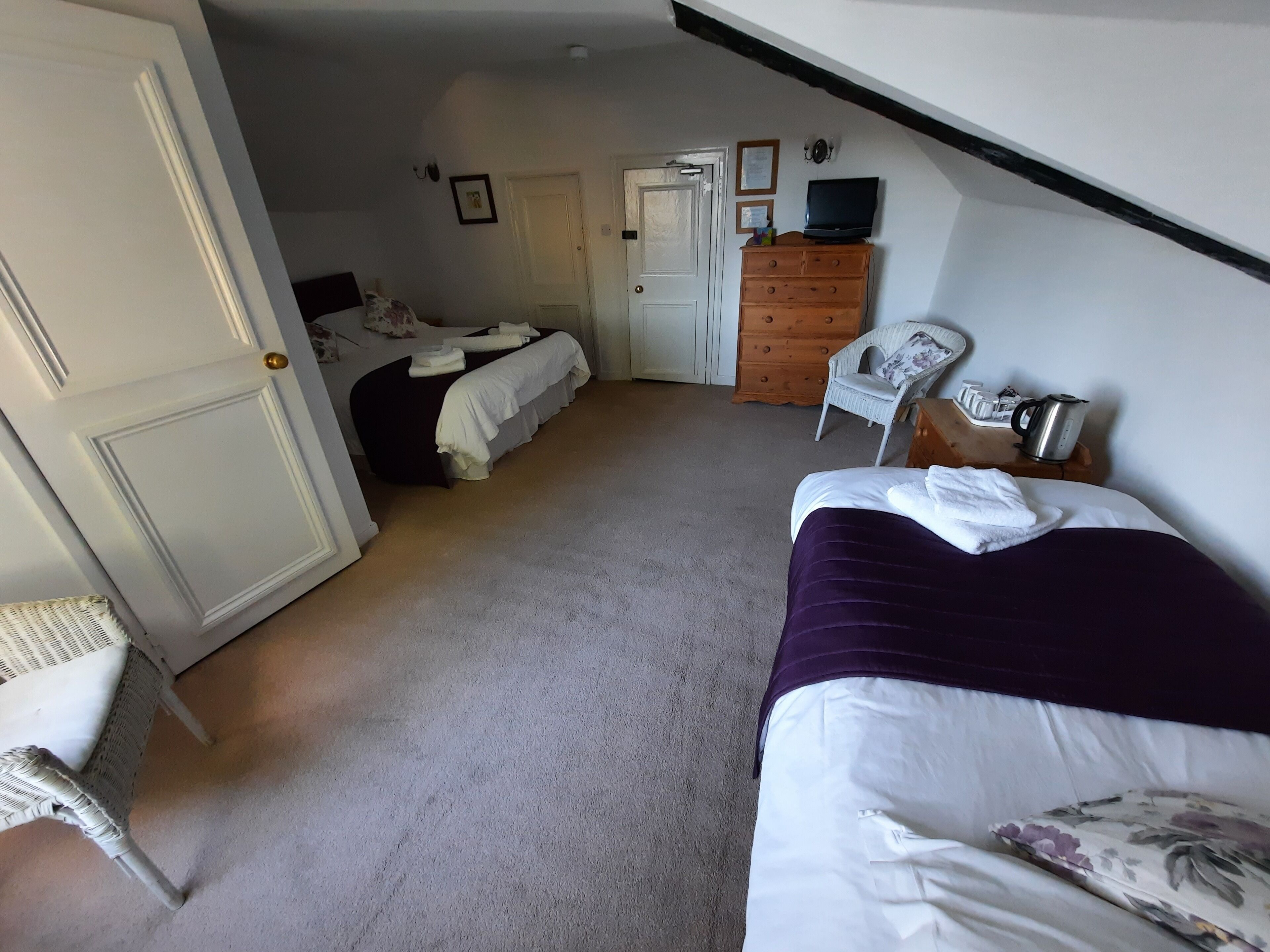 Ein Schlafzimmer mit zwei Betten, einem Schminktisch, einem Sessel und einem Fernseher.