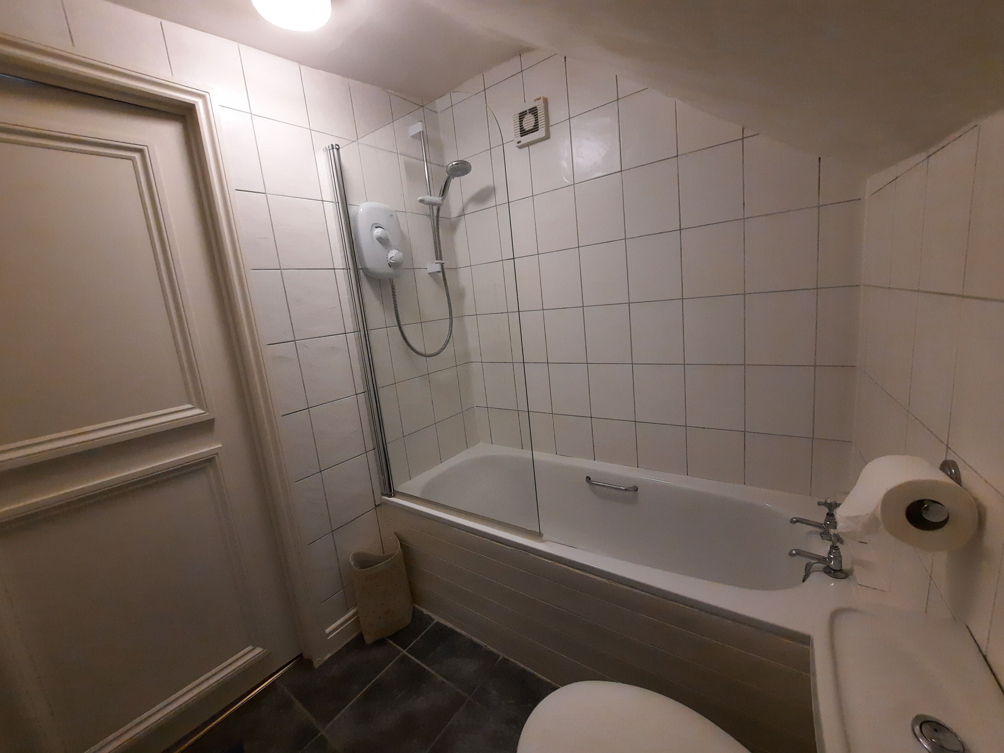 Een badkamer met een bad, toilet en douche.