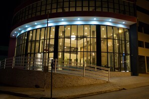 A modern building with a curved glass facade, a staircase leading to the entrance, and a well-lit exterior. - Minas Platinum Hotel & Convention (Conselheiro Lafaiete)