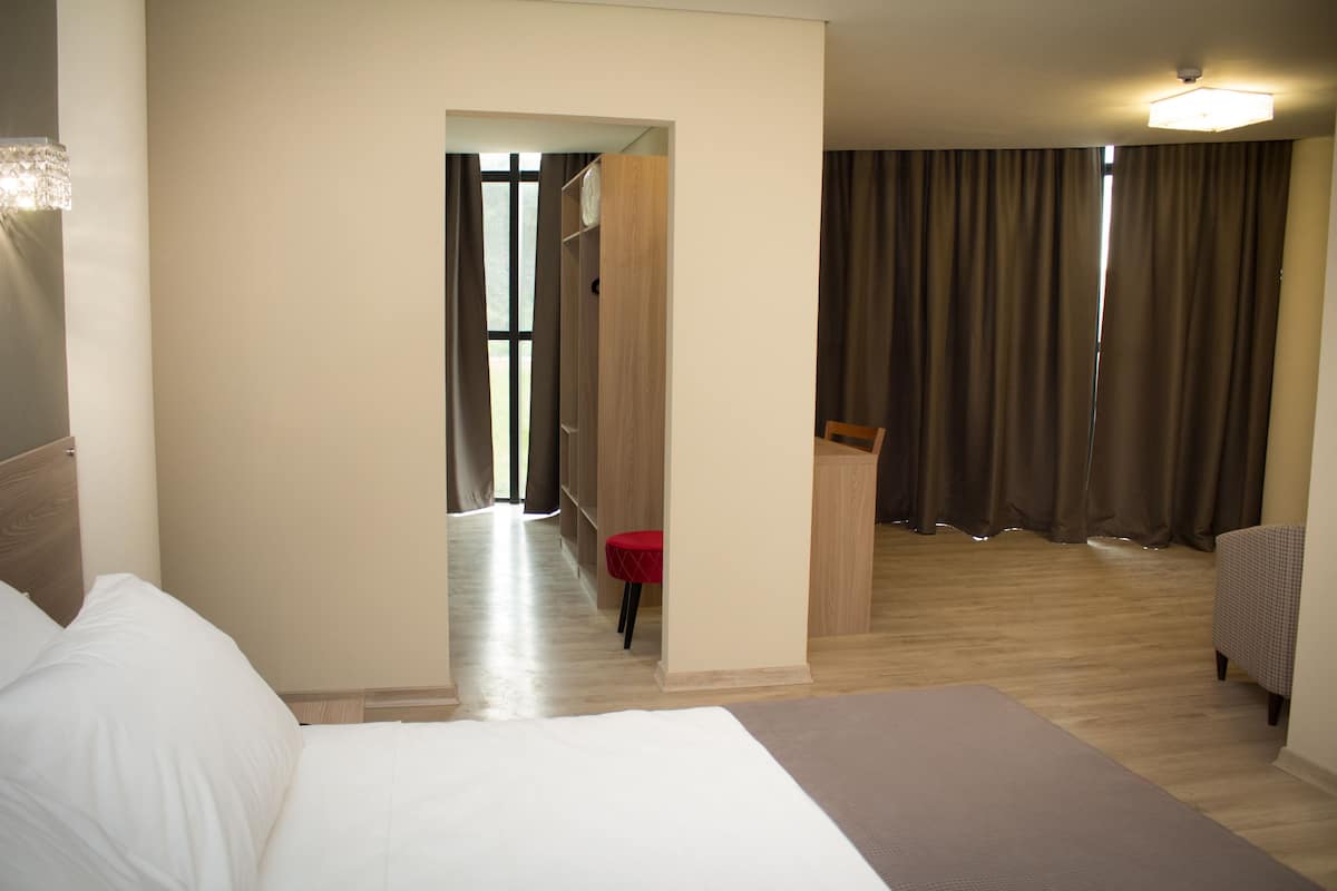 A hotel room with a bed, a desk, a chair, and a wardrobe.