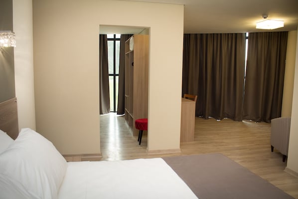 A hotel room with a bed, a desk, a chair, and a wardrobe. - Minas Platinum Hotel & Convention (Conselheiro Lafaiete)