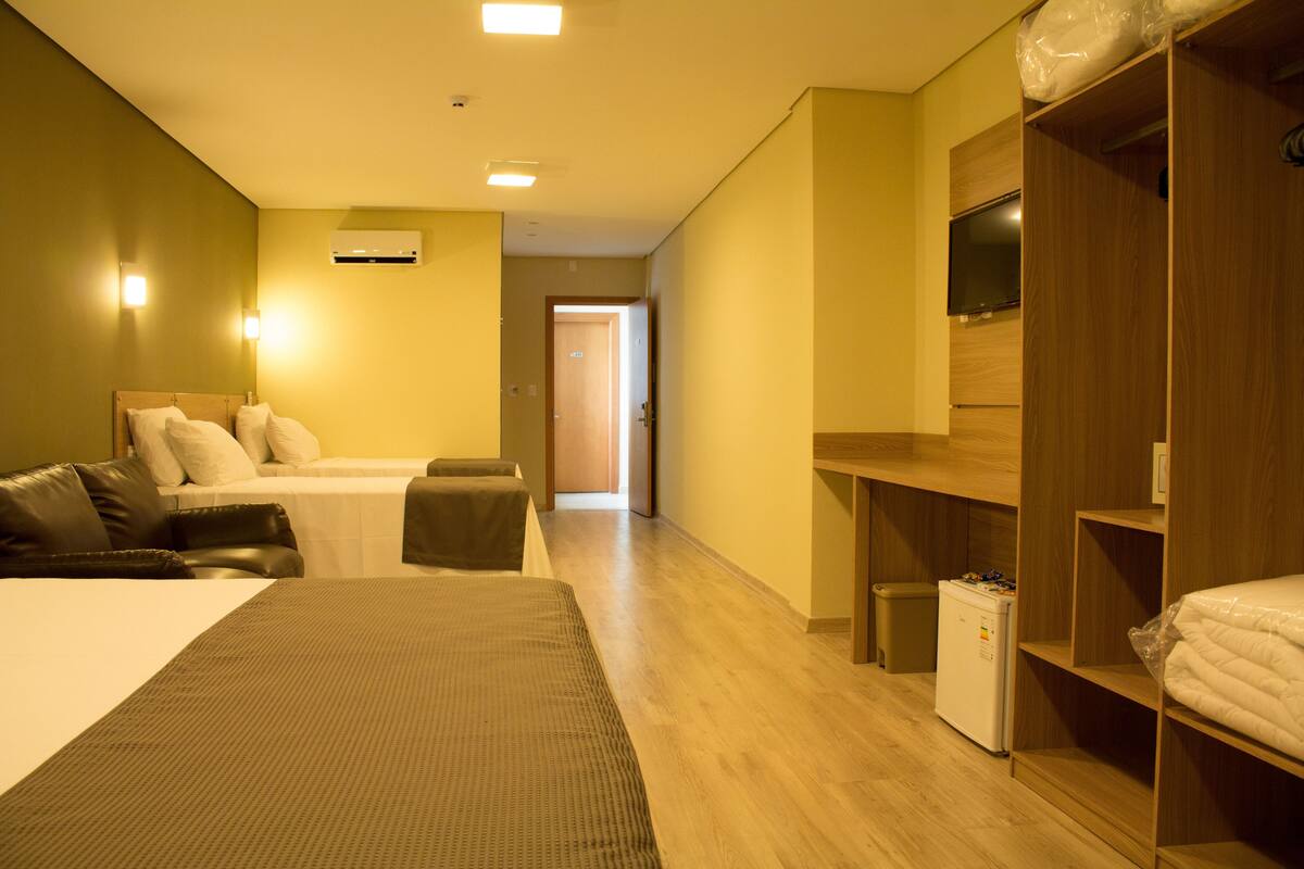 A hotel room with a large bed, a desk, a TV, and a wardrobe.