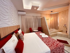 A hotel room with a large bed, a small table, a shower area, and a decorative wall. - Arlen Hotel (Pouso Alegre)