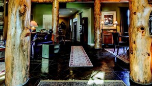 A spacious interior with a high ceiling, wooden beams, a central staircase, and a cozy seating area. - Yellowstone River Lodge (Columbus)