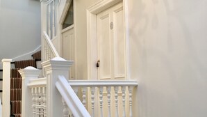 Un escalier avec des balustrades blanches et une main courante, menant à une porte sur laquelle est fixée une plaque nominative.