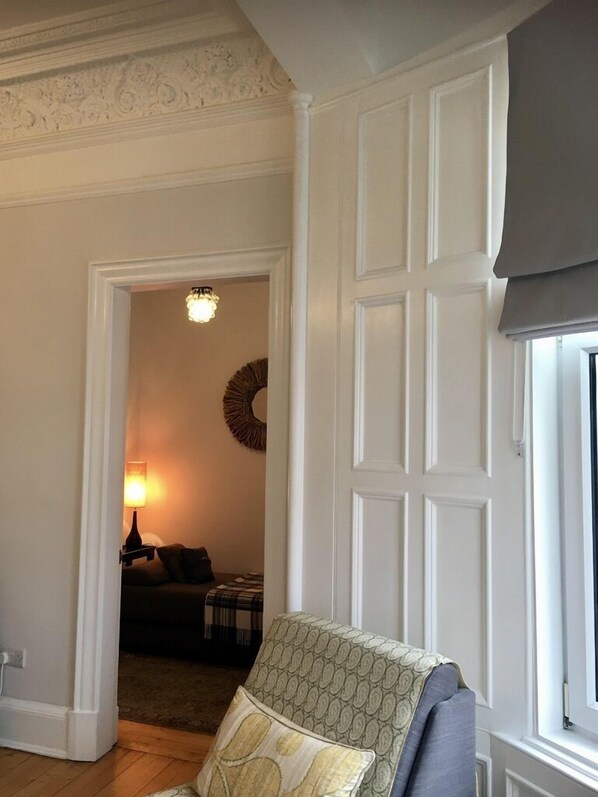 Une pièce avec un fauteuil à motifs, une porte dotée d’une fenêtre et un mur orné d’un décor en relief.