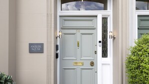 A light grey double door with a brass knocker, a small brass plate above the door, and a wall-mounted sign indicating the address. - Antler Guest House (Edinburgh)