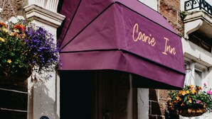 A Coorie Inn with a purple awning, a brick facade, and hanging flower baskets. - Coorie Inn Restaurant and Rooms (Crieff)