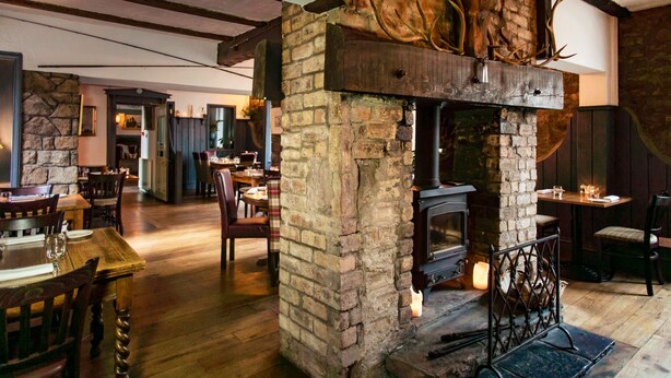A rustic interior with exposed brick walls, a stone fireplace, and wooden furniture. - Coorie Inn Restaurant and Rooms (Crieff)