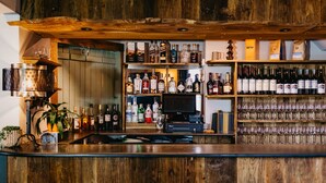 A bar area with wooden shelves stocked with various bottles and glasses. - Coorie Inn Restaurant and Rooms (Crieff)