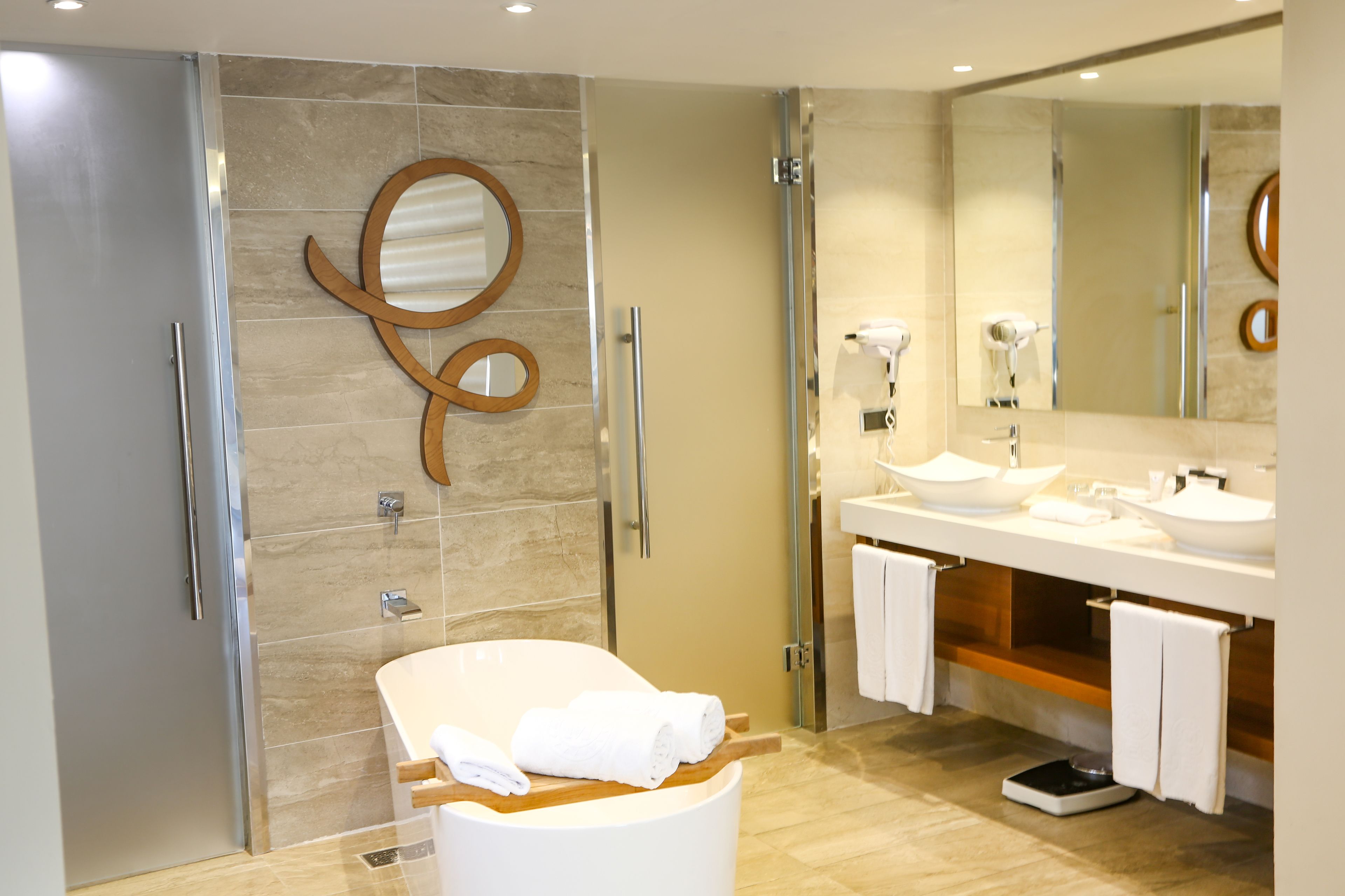 Un baño moderno con bañera, dos lavamanos, un espejo grande y zona de ducha.