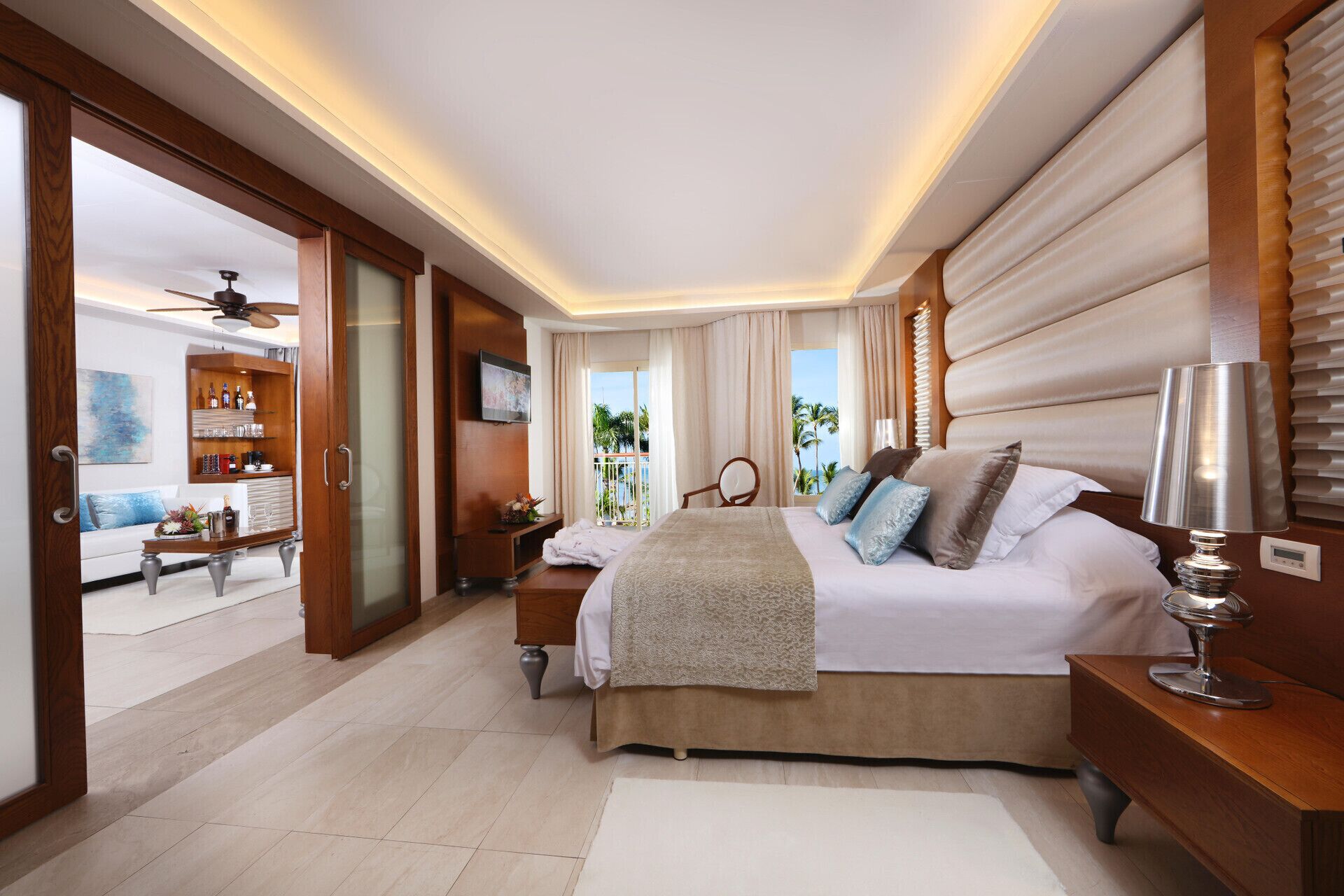 A spacious bedroom with a large bed, a TV, and a view of the ocean.