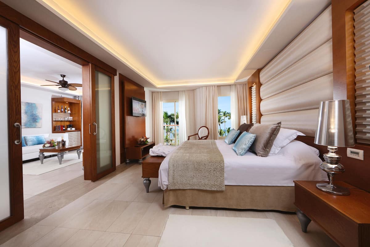 A spacious bedroom with a large bed, a TV, and a view of the ocean.