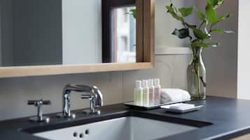 A bathroom with a mirror, sink, and a vase with a plant.