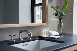 A bathroom with a sink, mirror, and toiletries.