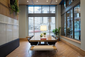 A conference room with a large table, chairs, a bench, a lamp, and potted plants. - Kimpton Schofield Hotel by IHG (Cleveland)
