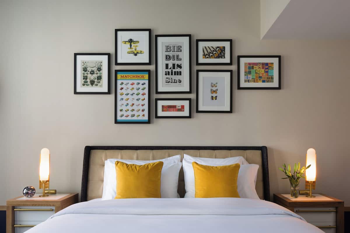 A neatly arranged bedroom with a bed, two bedside tables, and a wall adorned with framed artwork.