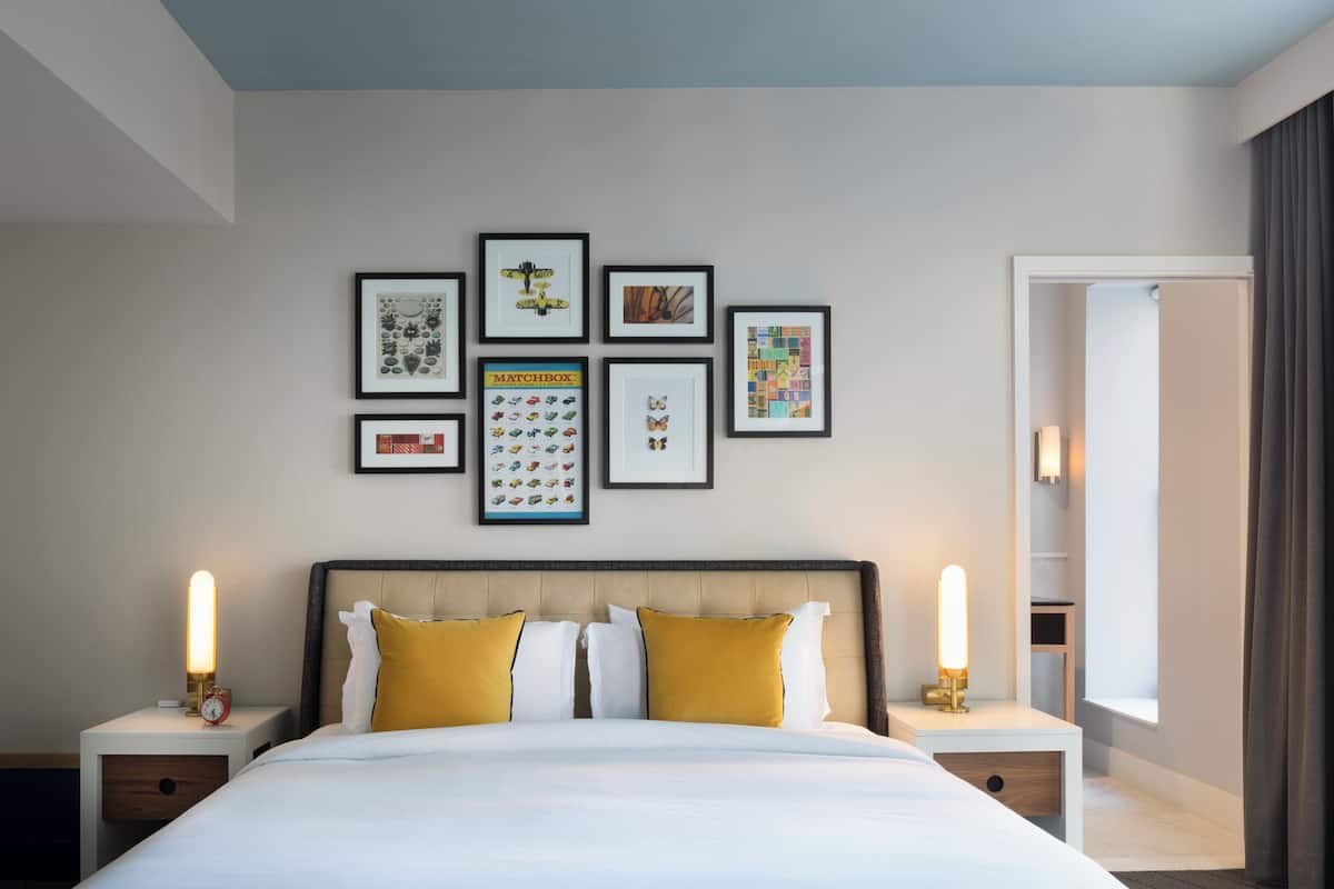 A hotel room with a large bed, two bedside tables, and a wall decorated with framed pictures.