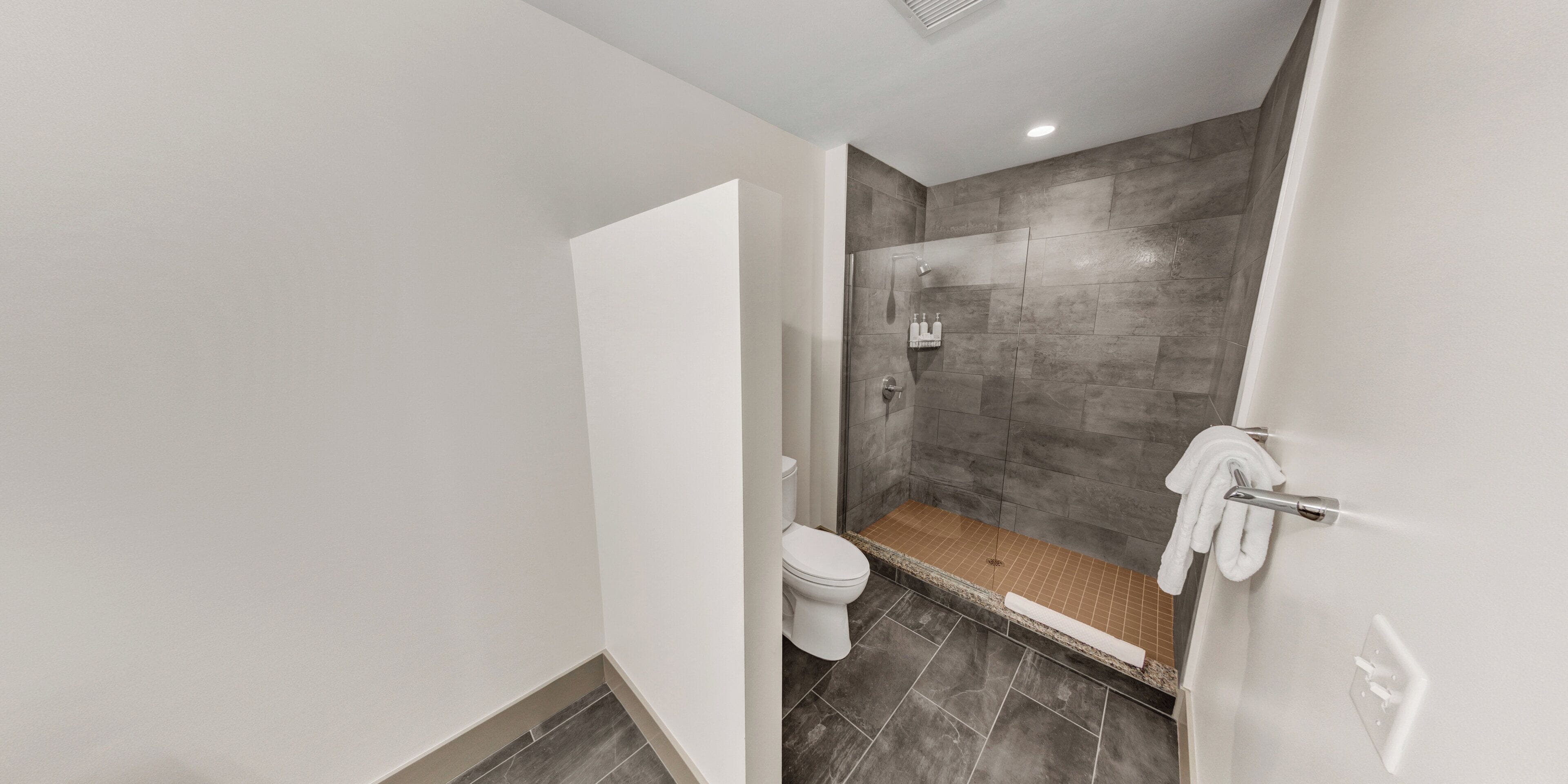 A modern bathroom with a shower, toilet, and a towel rack.