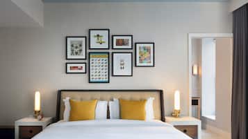 A hotel room with a large bed, two bedside tables, a wall with framed artwork, and a window with curtains.