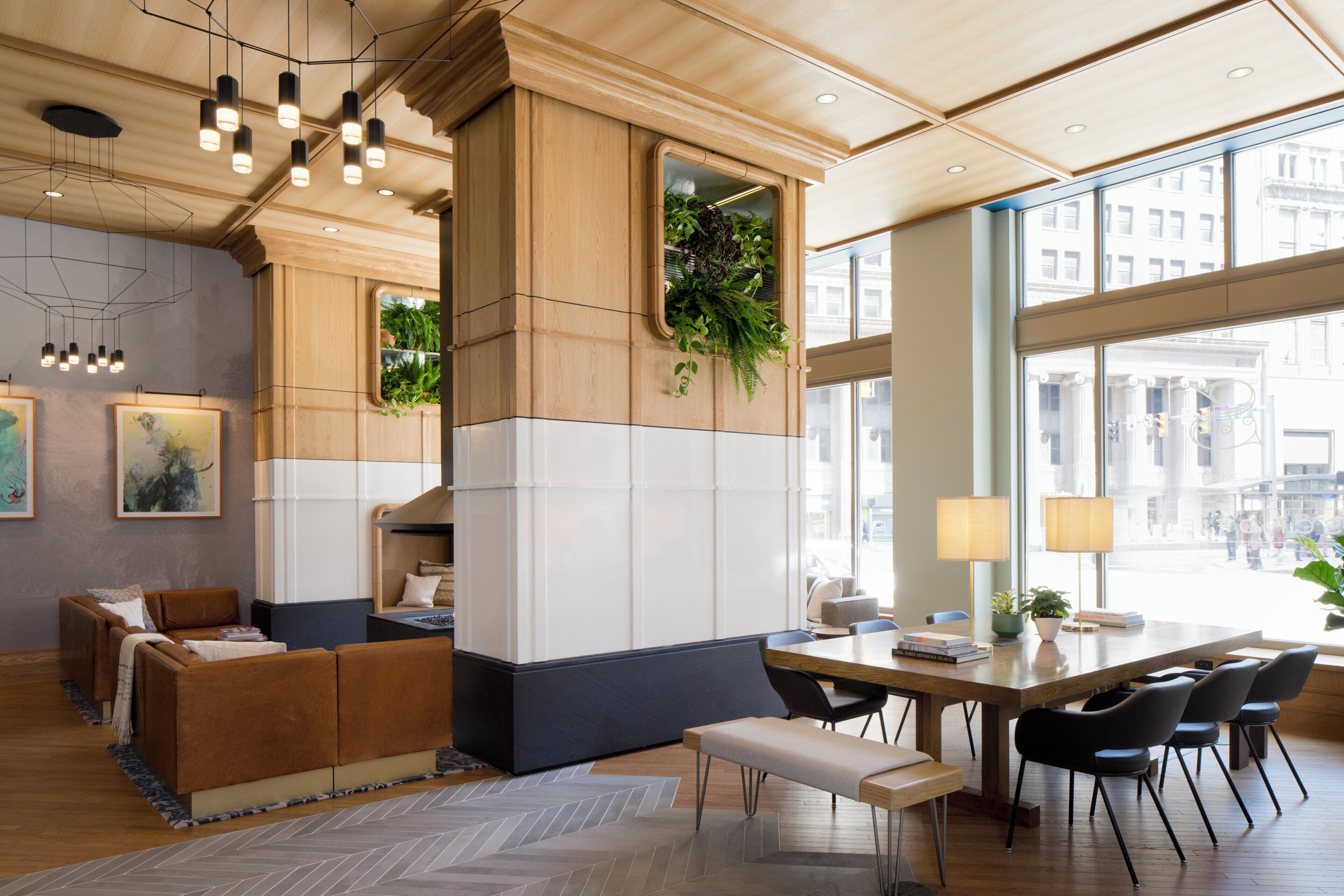 A modern interior with a wooden accent wall, a seating area with a bench and chairs, and a large window offering a view of the city.
