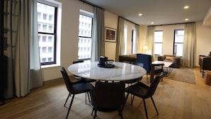 A modern hotel room with a round dining table, chairs, a sofa, and a small coffee table.