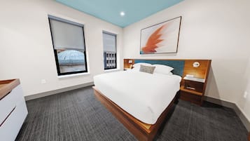 A modern hotel room with a large bed, a wooden headboard, a nightstand, and a window with a view of a dome structure.