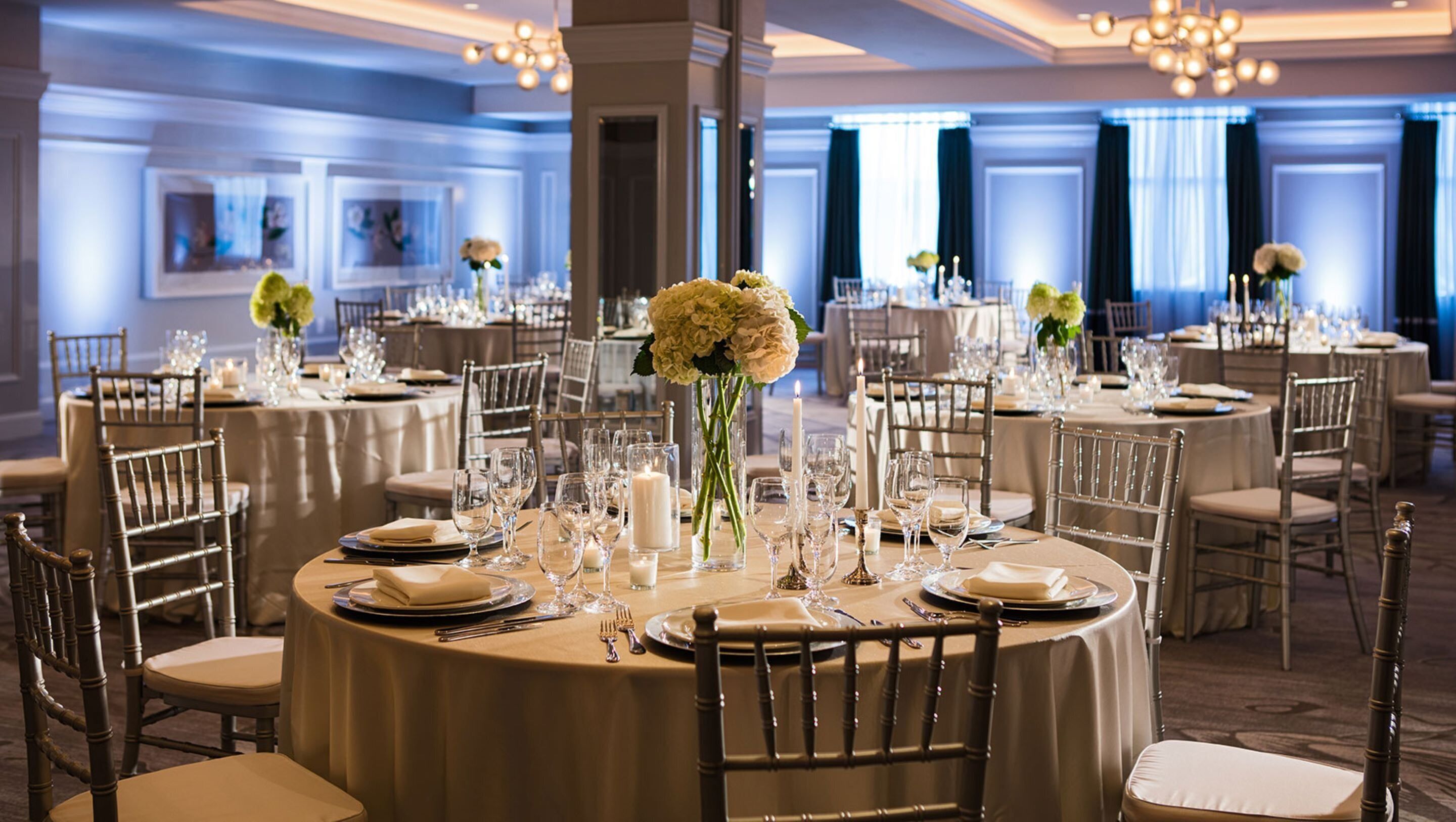 Un comedor formal con mesas redondas, manteles blancos y sillas elegantes.