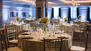 Un comedor formal con mesas redondas, manteles blancos y sillas elegantes.