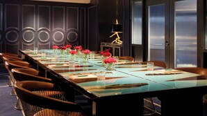 Une salle de conférence avec une longue table, des chaises et des vases remplis de fleurs.