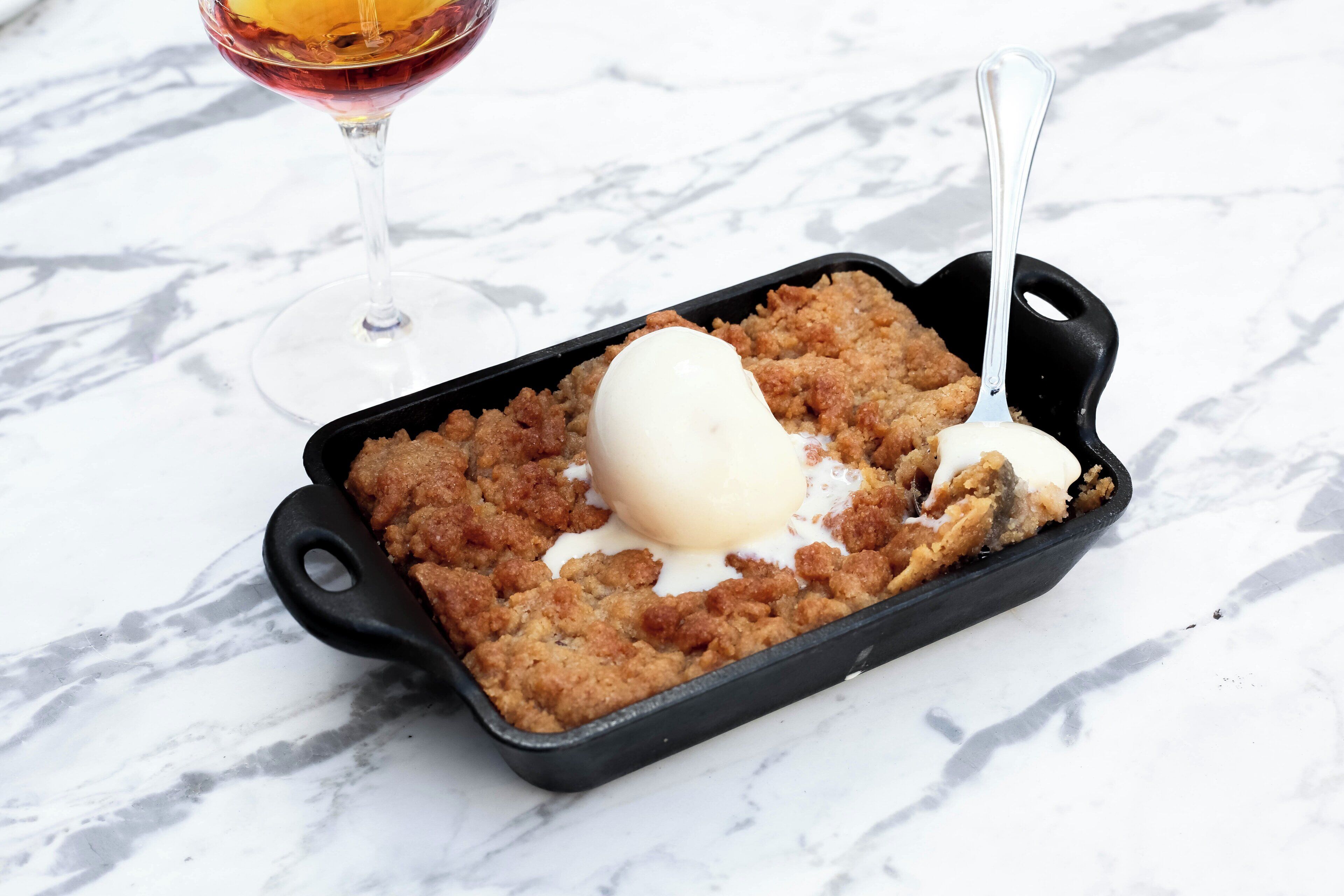 A dessert in a black cast iron skillet with a scoop of ice cream on top.