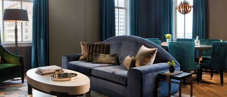 Un salon moderne avec un canapé bleu, une table basse ronde et un coin repas avec des chaises de couleur turquoise.