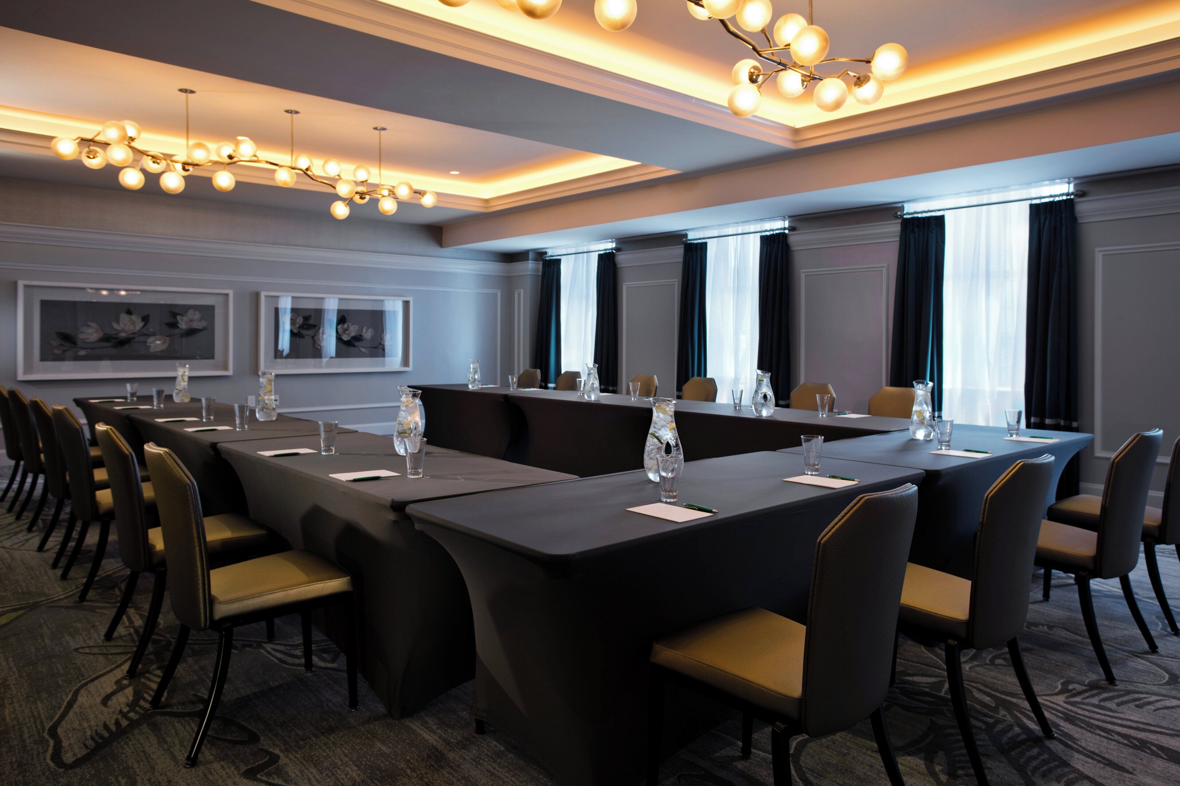 Une salle de conférence avec une longue table, des chaises et un lustre.
