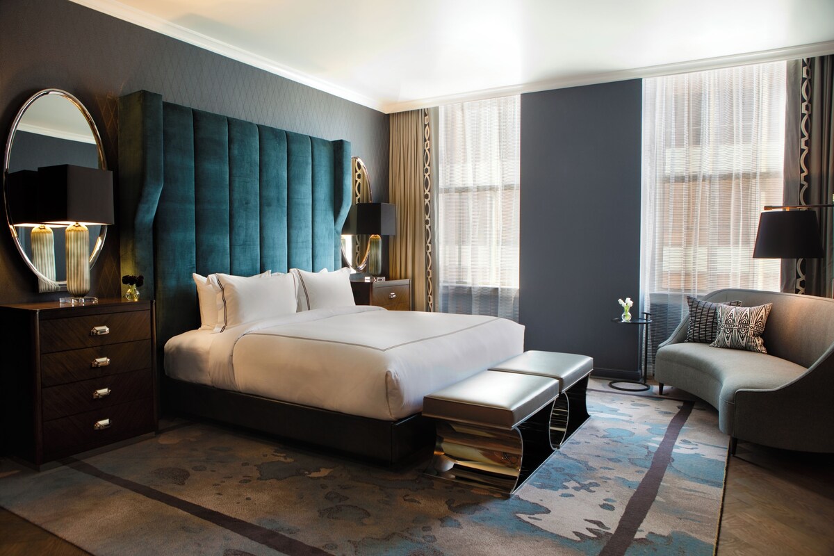 Una habitación de hotel moderna con una cama grande, un sofá, un escritorio y un espejo.