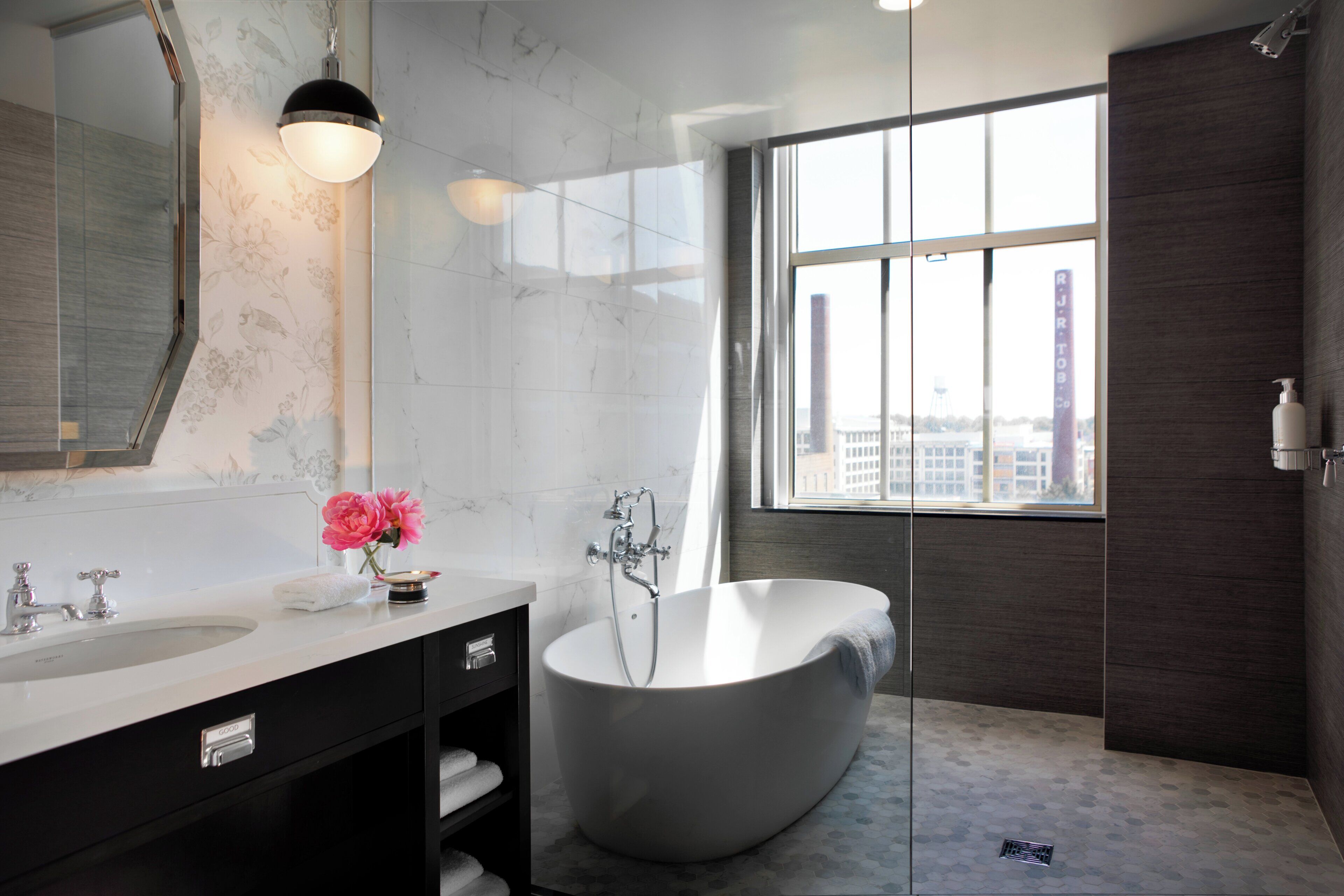 Un bagno moderno con una vasca freestanding, uno specchio grande e una finestra con vista sulla città.