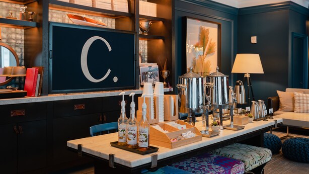 Un espace bar bien aménagé, avec des étagères, des bouteilles et un grand panneau en forme de « C ».